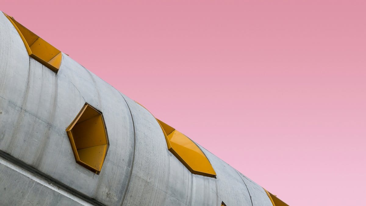 Sculptural curved concrete building with yellow details — Italian design aesthetic