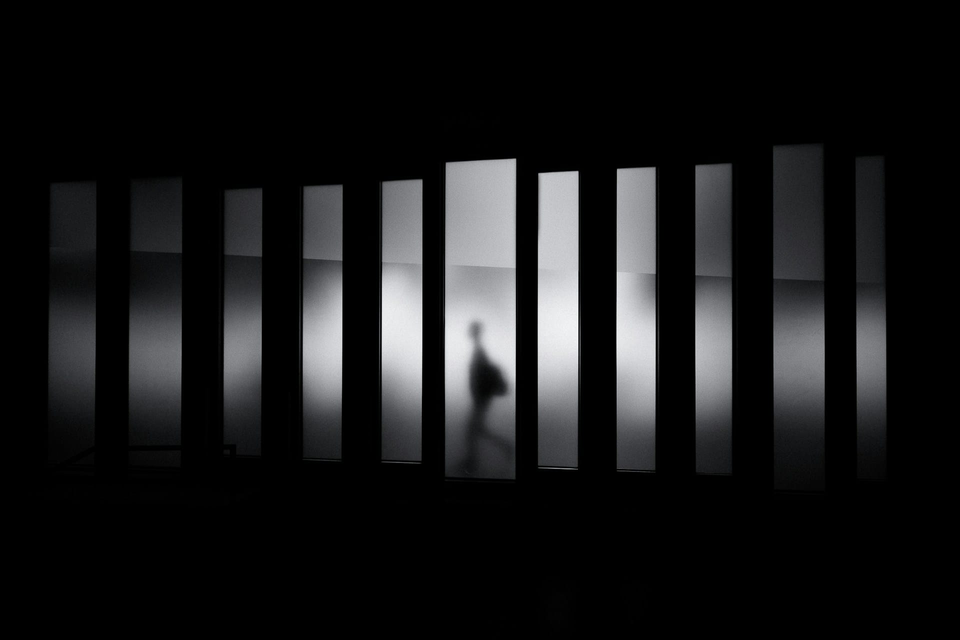 Minimalist architectural light installation with vertical panels and single figure silhouette