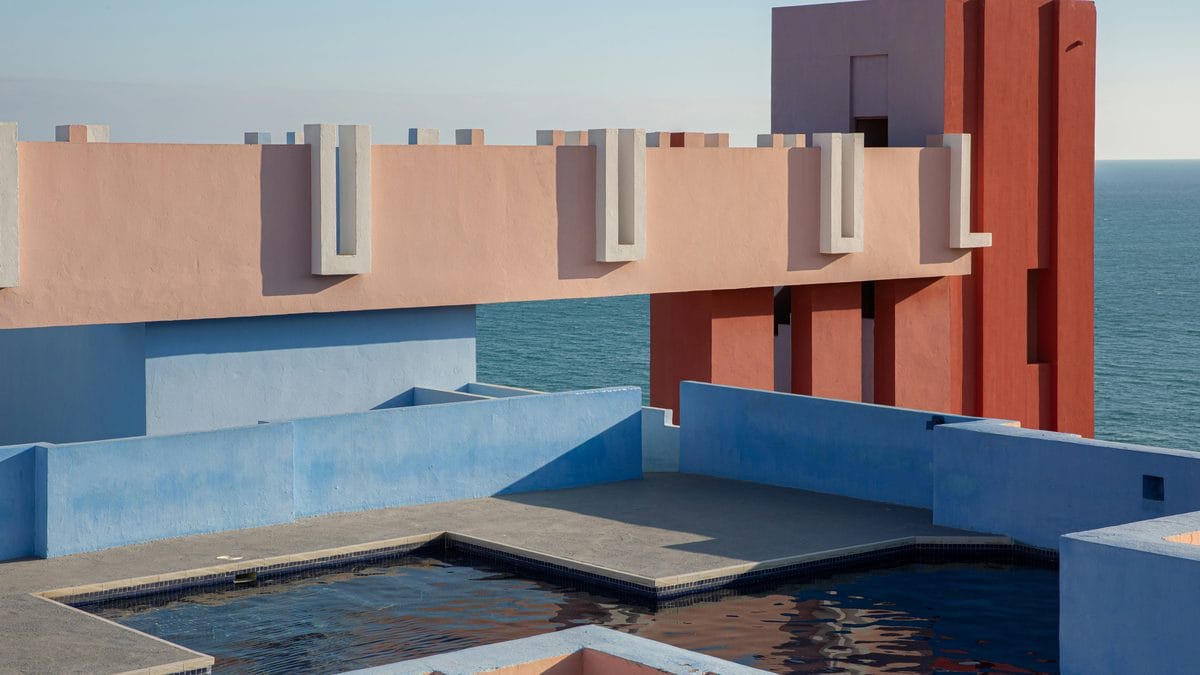 Ricardo Bofill La Muralla Roja pink and blue geometric architecture with rooftop pool and Mediterranean Sea