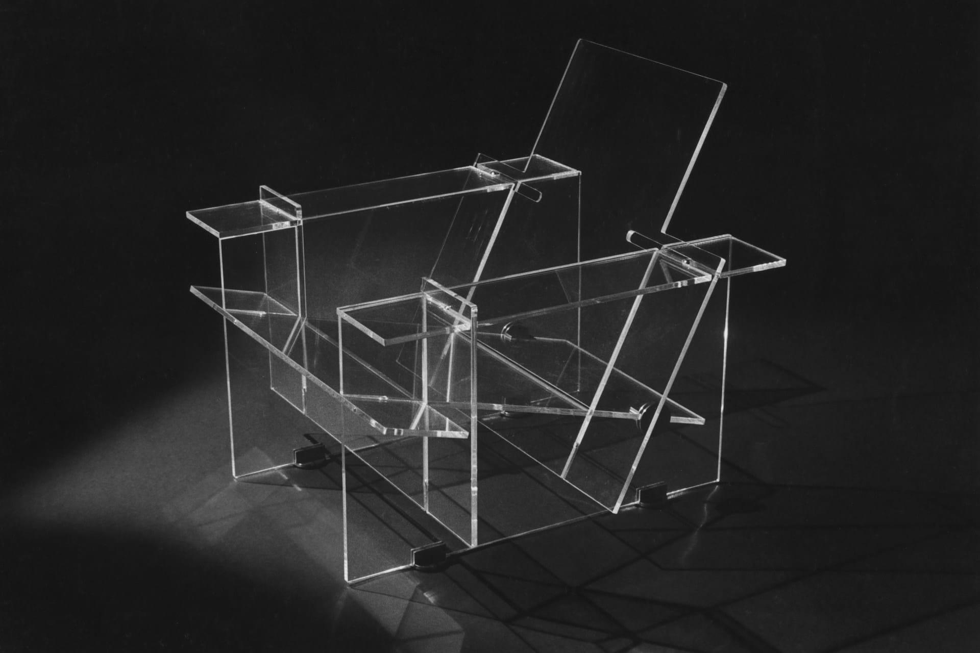 Clear acrylic chair construction model photographed in black and white studio lighting