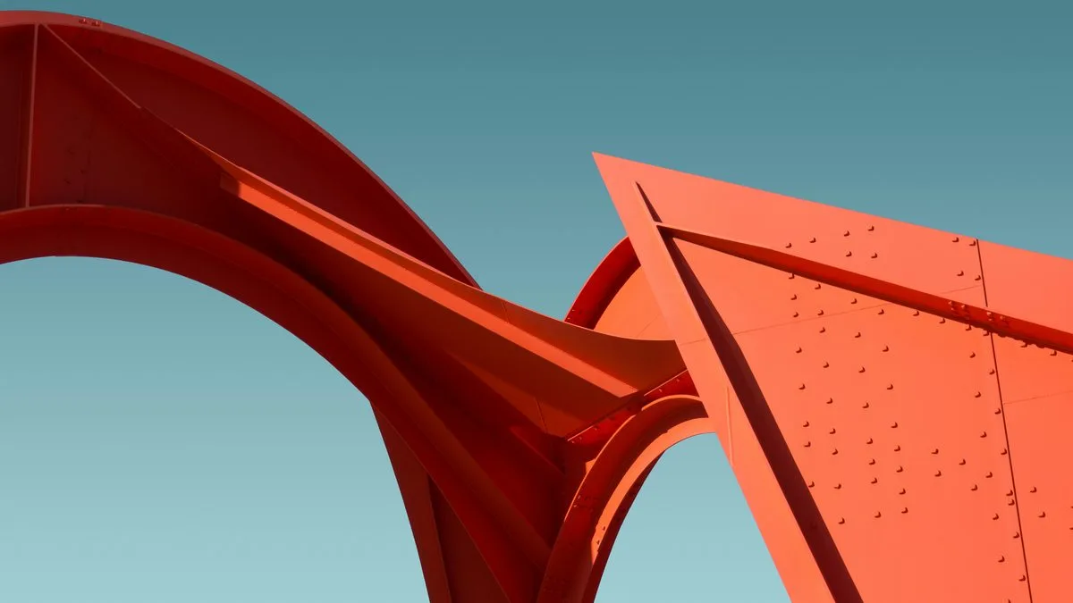 Red Calder-style steel sculpture with curved arches and riveted panels against a teal sky