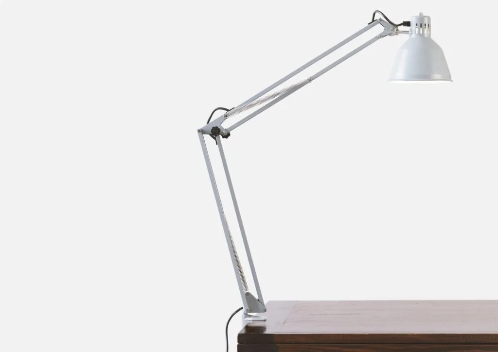 Balanced-arm desk lamp on wooden surface, Italian industrial design aesthetic