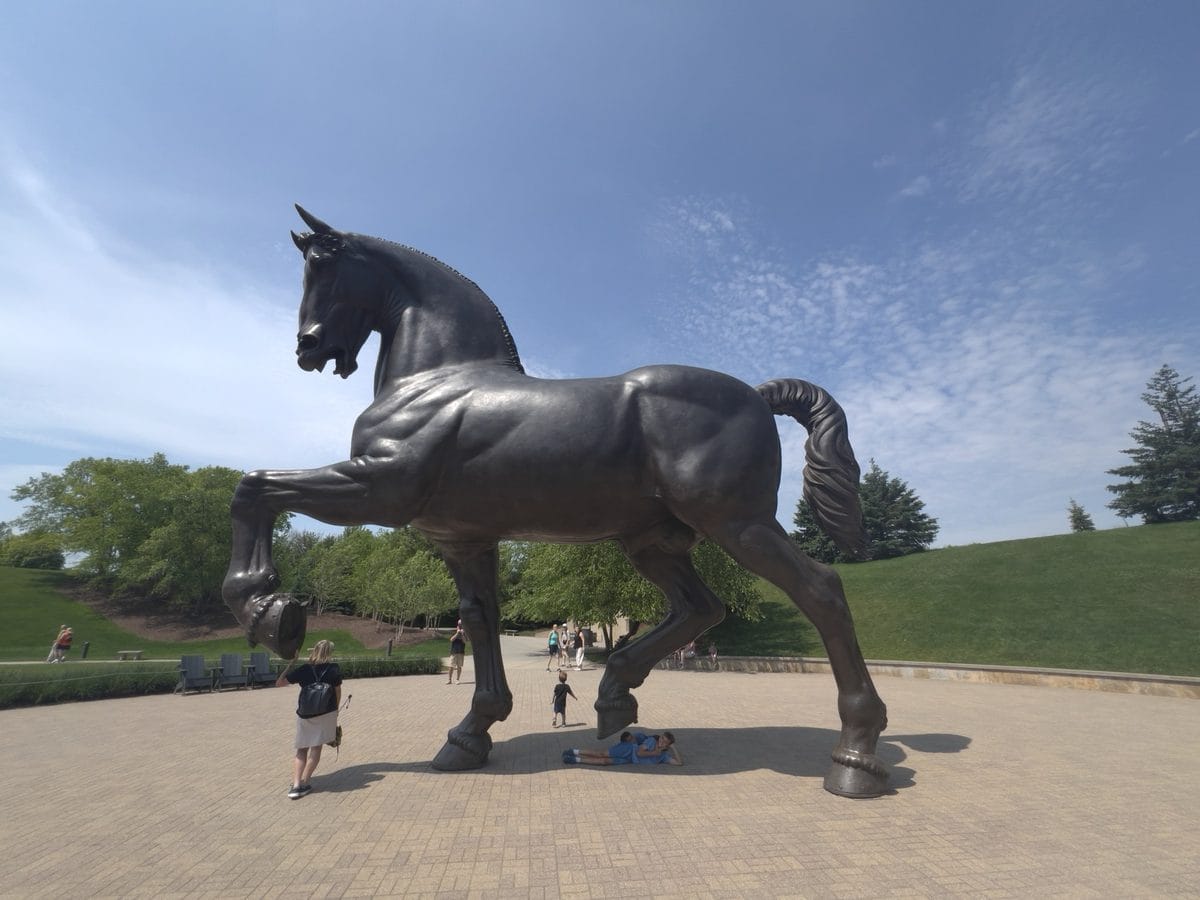 The American Horse sculpture with visitors at its base on the plaza at Frederik Meijer Gardens, Grand Rapids