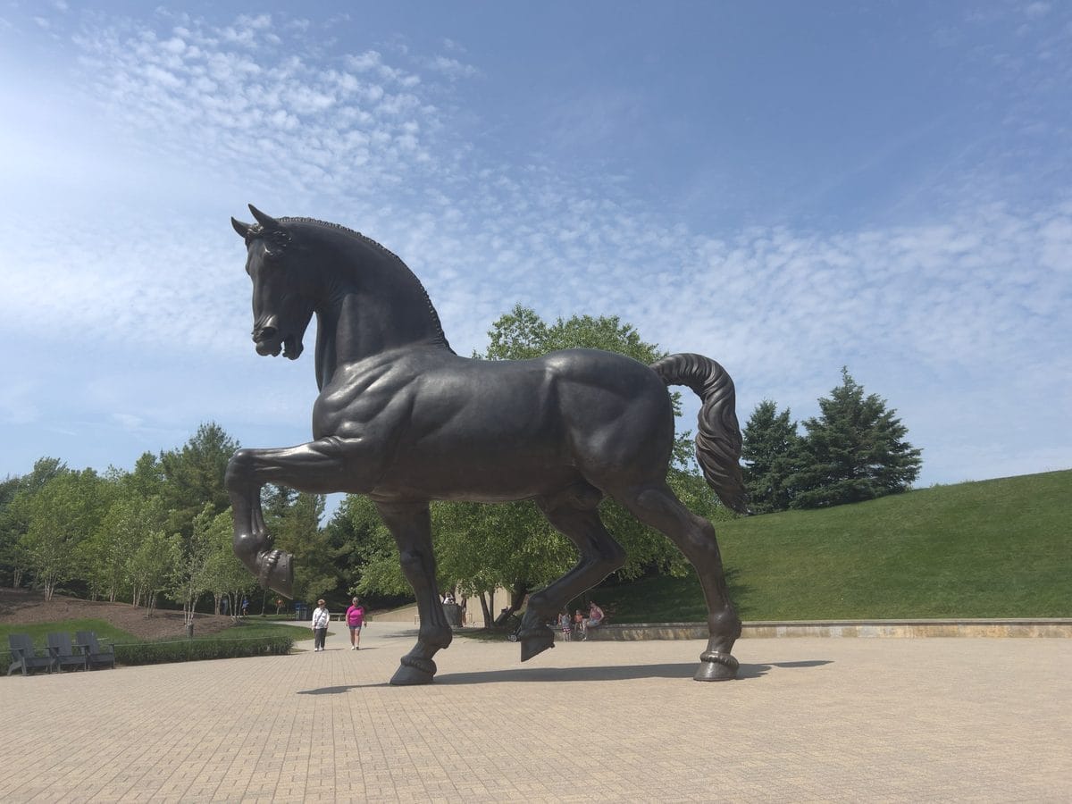 Visitors at the base of the 24-foot American Horse sculpture, showing its scale, at Frederik Meijer Gardens in Grand Rapids
